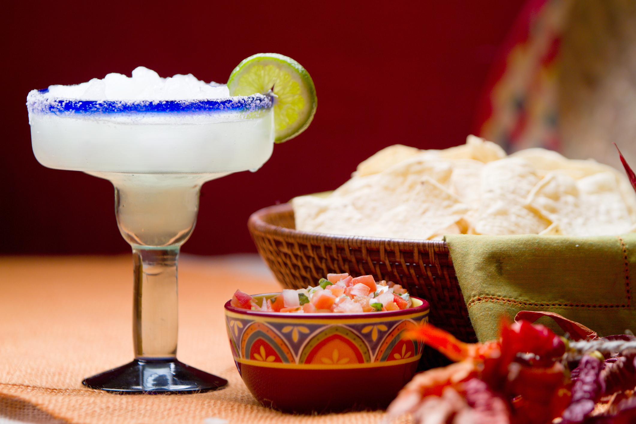 Traditional Mexican Chips, Salsa and Frozen Margarita with salt and lime on the rim of the glass on a table with Mexican decor.